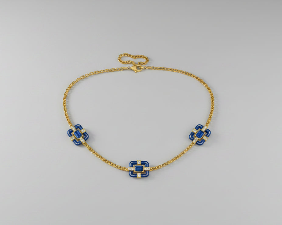 A delicate gold chain necklace featuring three small floral motifs, each accented with blue stones.