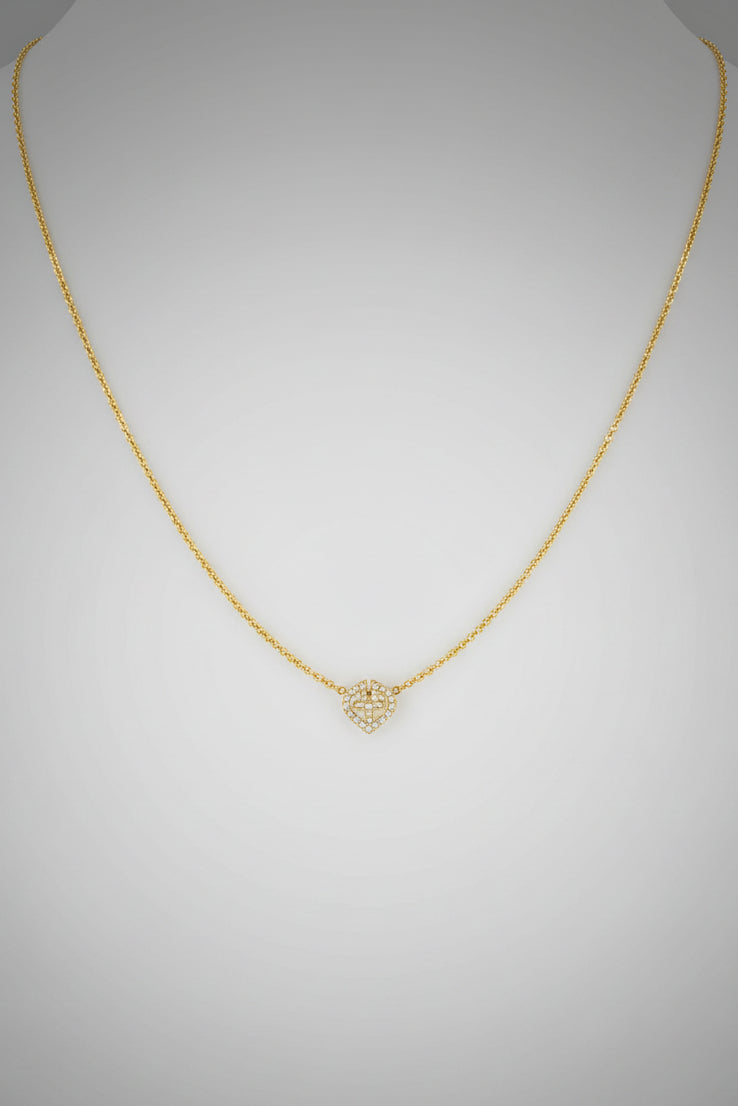 A delicate gold chain necklace with a small geometric pendant featuring a stylized 'V' design.